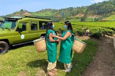 two women standing in front of a green vehicle