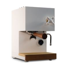 an espresso machine sitting on top of a wooden shelf next to a white wall