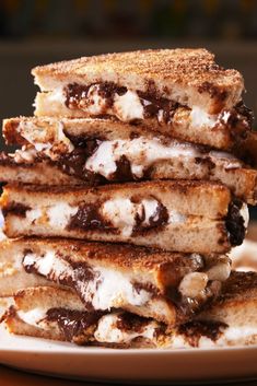 a stack of grilled cheese sandwiches sitting on top of a white plate with chocolate sauce and marshmallows