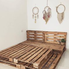 a bed made out of wooden pallets in a room with two hanging dream catchers on the wall