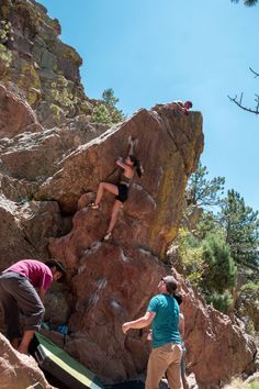 two people climbing up the side of a mountain