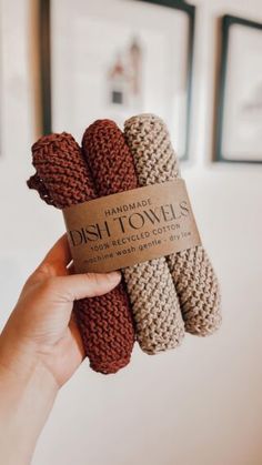 handmade dish towels in brown, beige and tan colors are held up by a woman's hand