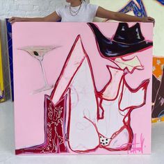 a woman standing next to a pink painting with heels and a hat on it's head