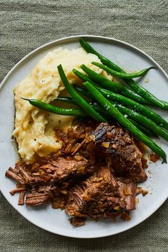 a white plate topped with meat, mashed potatoes and green beans