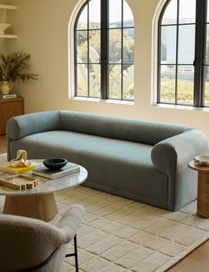 a living room with two large windows and a blue couch in front of the window