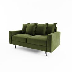 a green couch sitting on top of a white floor next to two pillowed pillows