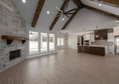 an empty living room with wood flooring and exposed ceiling beams in the kitchen area