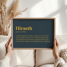 a person holding up a framed sign that says hirath in gold on it