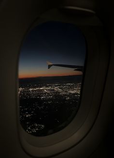 an airplane window looking out at the city lights