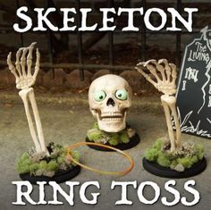 three fake skeleton heads with green eyes and hands on top of small bases in front of a sign that says, ring toss