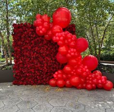 red balloons are floating in the air next to a sculpture made out of flowers and plants