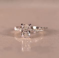 an engagement ring with a princess cut diamond in the center and side stones on each band