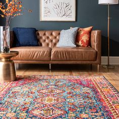 a brown leather couch sitting on top of a wooden floor next to a blue wall