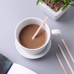 a cup of hot chocolate next to some wooden utensils and a potted plant