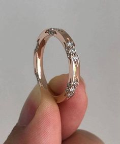 someone is holding a wedding ring with diamonds on the inside and outside, in front of a white background