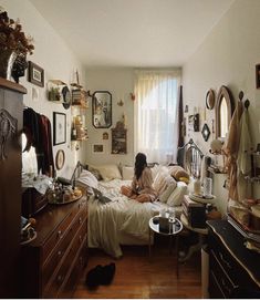 a woman sitting on a bed in a room with lots of clutter and decorations