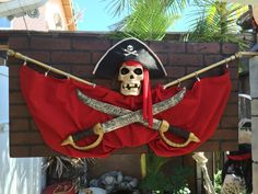 a pirate costume hanging on the side of a building with two swords and a skull