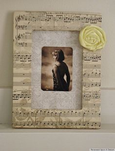 an old photo frame with music notes and a yellow flower on the wall next to it