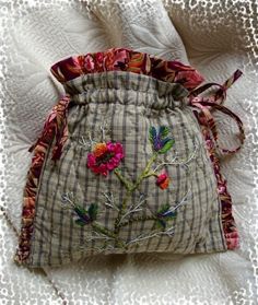 a small bag with flowers on it sitting on a bed