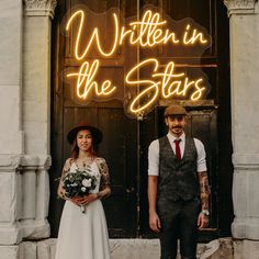 a man and woman standing in front of a building with the words written on it