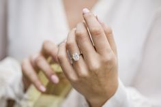 a woman wearing a diamond ring holding a bottle