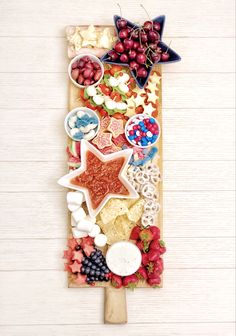 a cutting board with fruits and crackers arranged on it, including grapes, strawberries, cherries, blueberries, raspberries