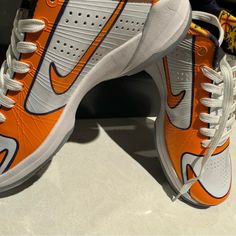 an orange and white tennis shoe on display