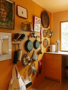 a kitchen wall with pots and pans hanging on it's side, next to a window