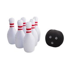 the bowling ball is next to some white bowling pins and a black one with red stripes