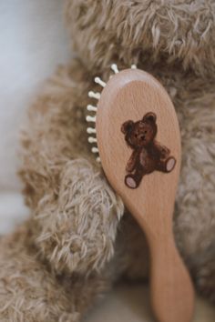 a brown teddy bear holding a wooden comb