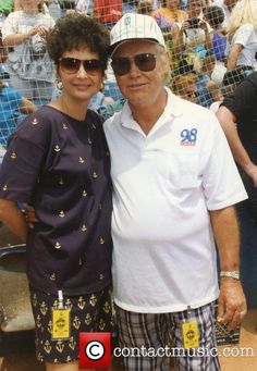 an older man and woman standing next to each other in front of a cage full of people