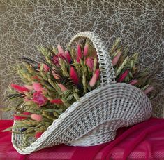 a wicker basket with pink flowers in it