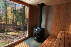 a wooden sauna with a large window looking out onto the woods