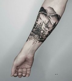 a man's arm with trees and mountains on it