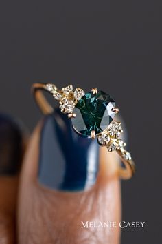 a woman's hand holding a ring with a green and white diamond on it