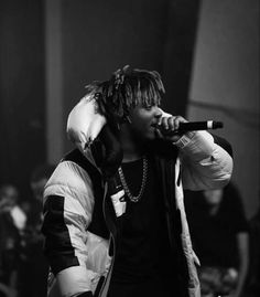 a man with dreadlocks holding a microphone up to his ear while standing in front of a crowd