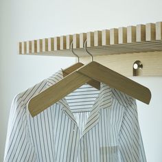 a shirt hanging on a clothes hanger in front of a white wall with wooden slats