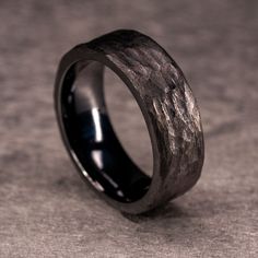 black ceramic ring with wood inlays on the outside and inside, sitting on a gray surface