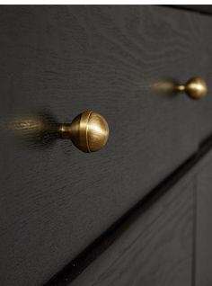 a close up of a black dresser with gold handles and knobs on the drawers