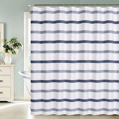 a blue and white striped shower curtain in a bathroom with a bathtub, mirror and dresser