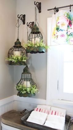 three bird cages hanging from the ceiling above a toilet in a bathroom with flowers on it