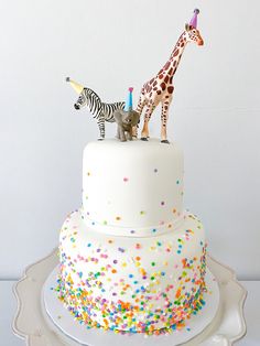 two giraffes on top of a white cake with sprinkles