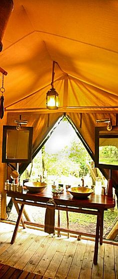 the inside of a tent with wooden flooring and tables in front of a window