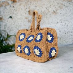 a crocheted handbag sitting on top of a white table next to a plant