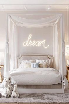 a white canopy bed with the word dream written on it