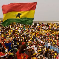 a large group of people standing in front of a crowd holding flags and wearing hats