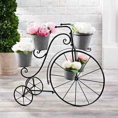 an old fashioned bicycle with flower pots on the front wheel is sitting on a wooden floor