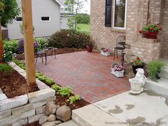 a brick patio with potted plants and flowers on the ground next to a house