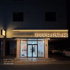 a lighted sign on the side of a building that says touch line me at night