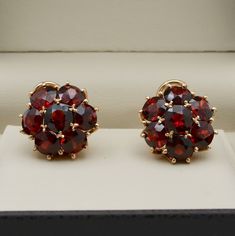 "A pair of vintage \"gemmy\" garnet cluster ear clips set in solid 18K gold with the richest red wine hue and a mesmerizing glow.  The round cut garnets are intricately set in a dome shaped design and together, weigh approximately 11 carats.  Earring posts can easily be added or we can convert these into a pair of dangling earrings!  A matching ring is available and listed separately on the website. Metal: 18K Rosy Yellow Gold Weight: 10.6 grams Garnets: Approximately 11 carats Measurements: 0.6 Red Cluster Earrings For Formal Events, Red Cluster Earrings Fine Jewelry For Formal Events, Red Cluster Earrings For Formal Occasions, 14k Gold Cluster Earrings For Formal Occasions, Formal 14k Gold Cluster Earrings, Classic Garnet Earrings For Anniversary, Yellow Gold Garnet Earrings For Anniversary, Classic Round Garnet Earrings, Yellow Gold Garnet Round Earrings